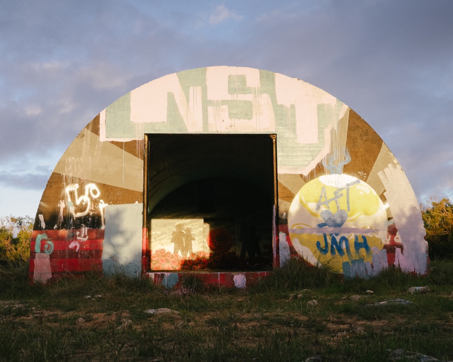 Painted curved exterior of the RAAF bunker in Yanchep, with a doorway and poppy mural