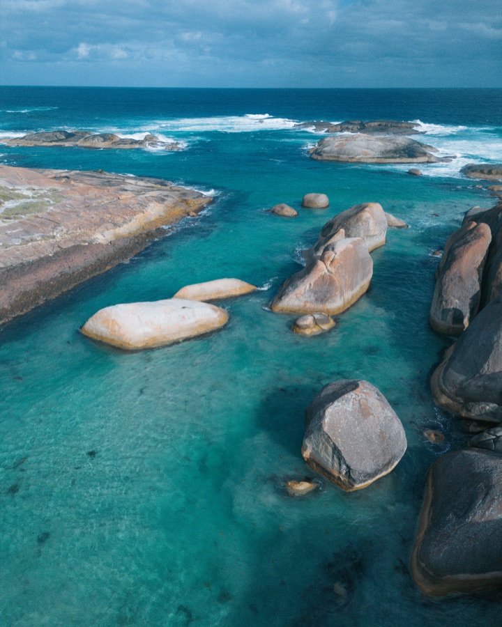 Aerial view of pale rounded boulders surrounded by clear turquoise water