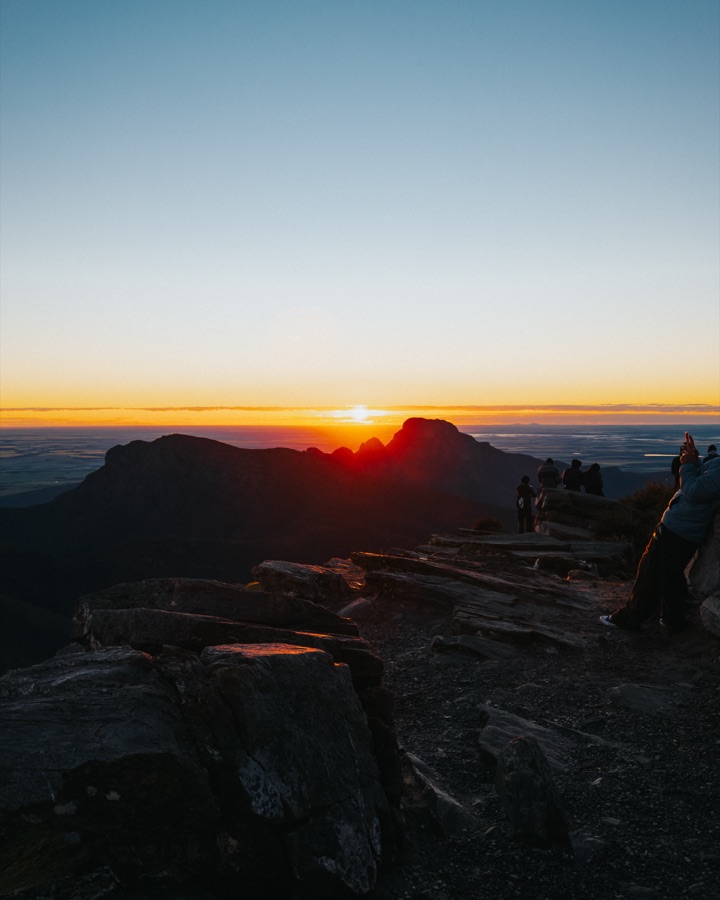 The sun rising over distant mountain ridges from Bluff Knoll